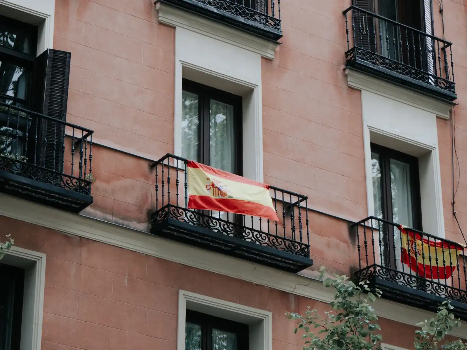 Een roze gevel in Madrid met smeedijzeren balkons en een Spaanse vlag