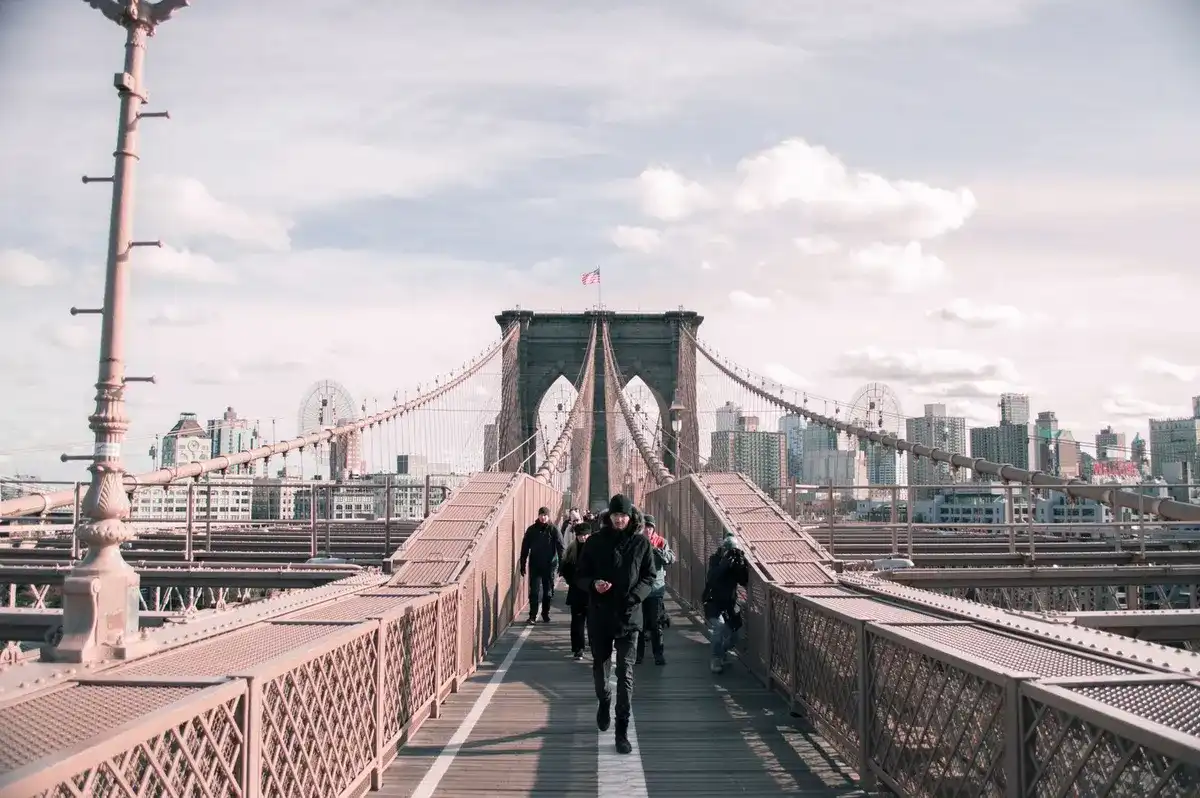 Gente cruzando a pie el puente de Brooklyn con el skyline de Manhattan al fondo
