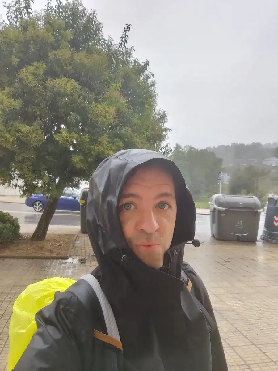 Michiel Das con la capucha puesta bajo la lluvia, en una calle mojada