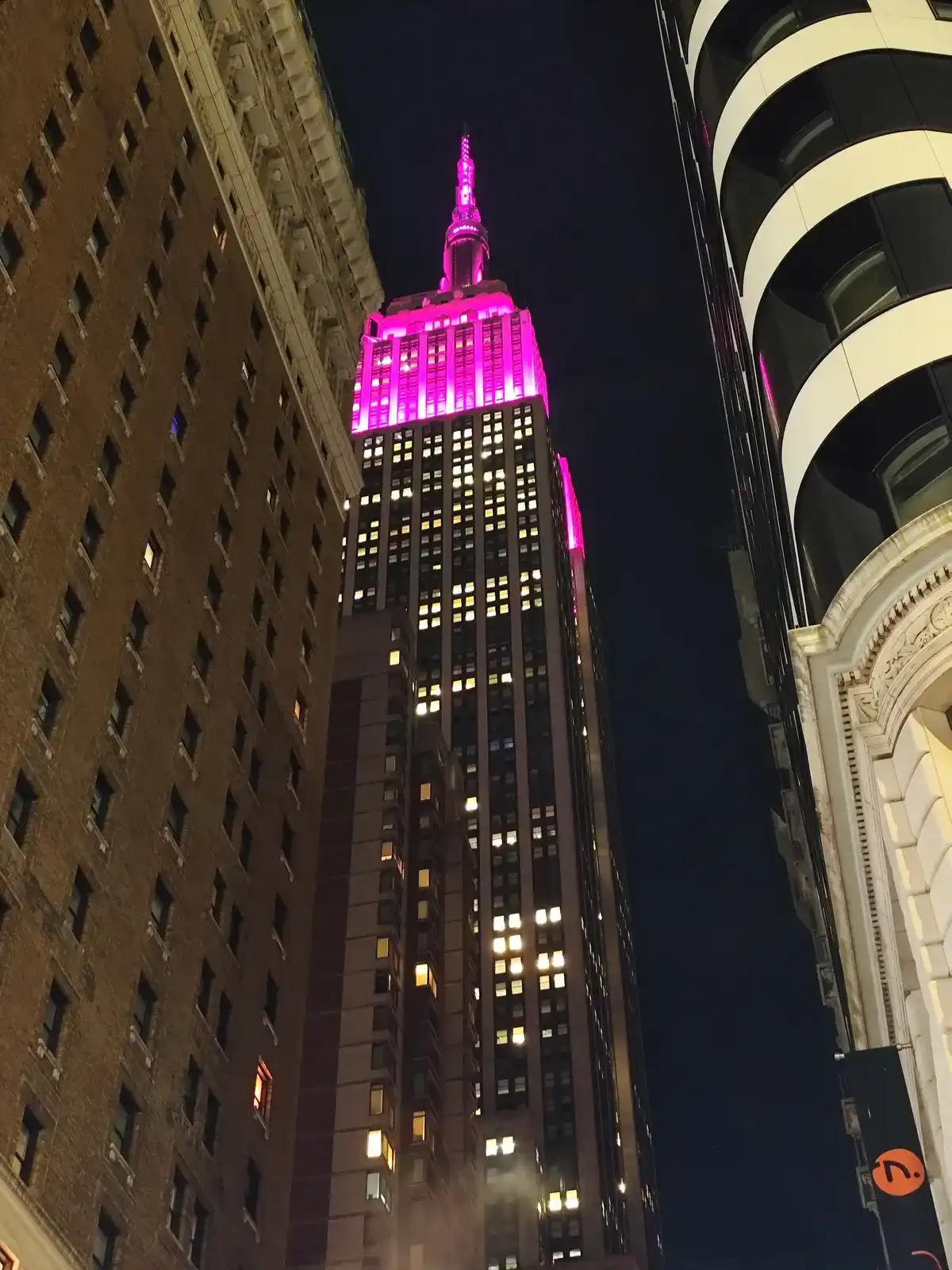 El Empire State Building iluminado de rosa visto desde la calle de noche