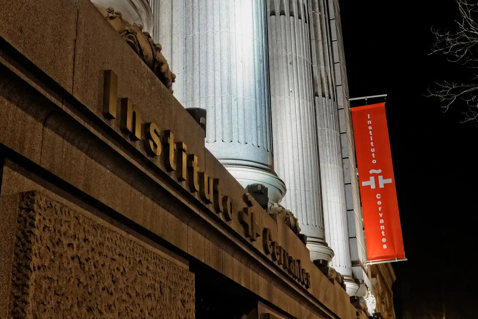 De ingang van het Instituto Cervantes in Madrid met zijn naam in de gevel en een rode banier