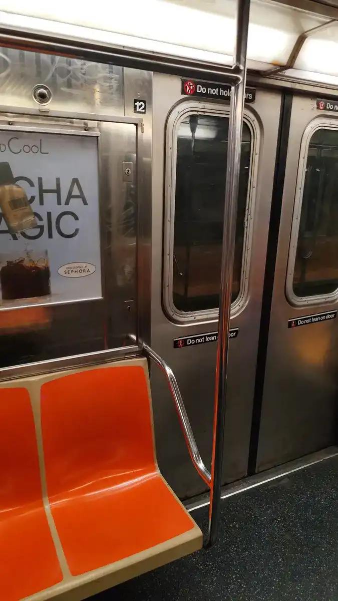 Interior de un vagón del metro de Nueva York, con el aviso Do not lean on door en las puertas