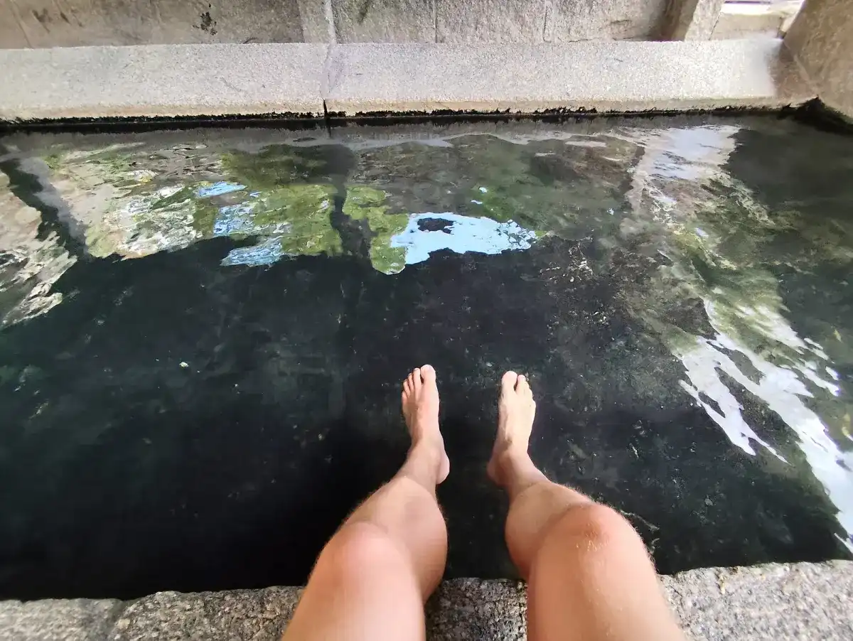 Pies metidos en el agua de la fuente termal pública de Caldas de Reis