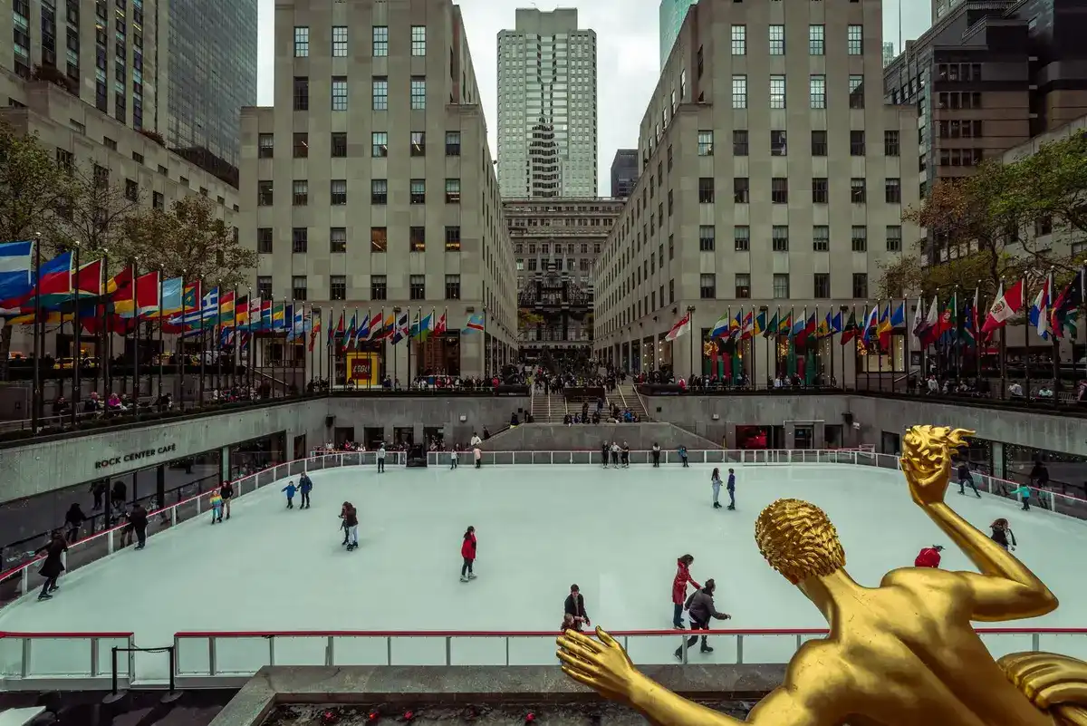 Patinadores en la pista de hielo del Rockefeller Center con la estatua dorada de Prometeo