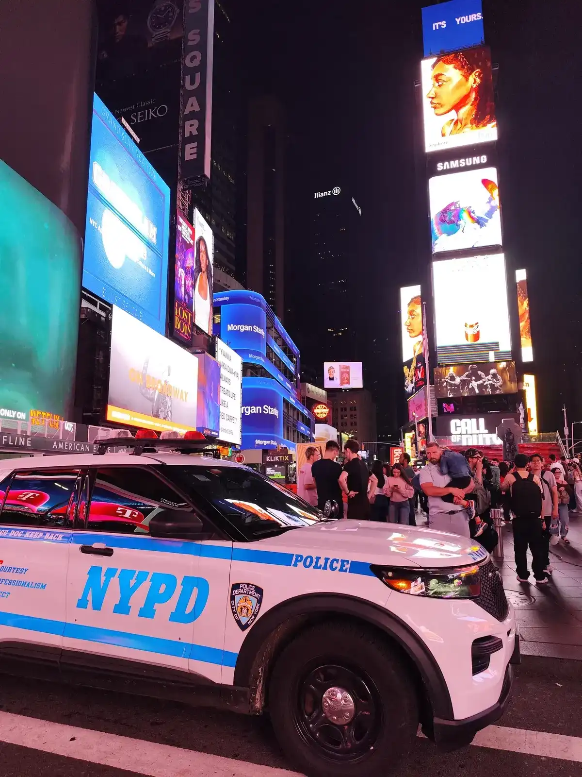 Times Square bij nacht met een politiewagen van de NYPD voor de schermen