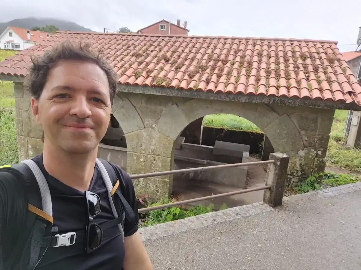 Michiel Das con la mochila en la última pausa antes de Santiago, junto a una construcción de piedra con tejado